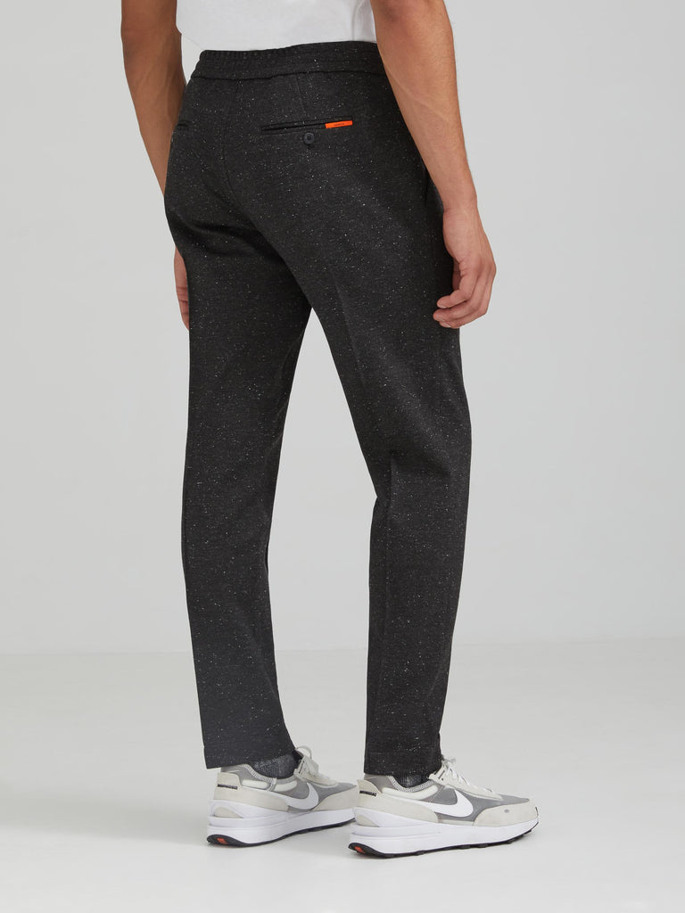 The Vanta Pant by SENECA in Charcoal Donegal. Performance AYR fabric from Italy: 4-way stretch, exceptionally soft, machine washable, wrinkle resistant. Comfortable and versatile men's trousers with elastic waistband, 4 pockets, and a button zipper fly. Replace your chinos, jeans, and khakis perfect for back to the office. Back view.