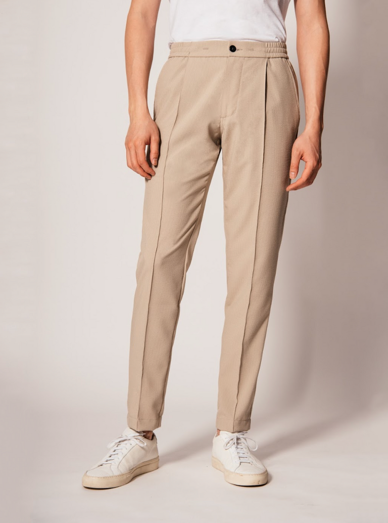 The Vanta Pant by SENECA in Khaki Seersucker. Comfortable and versatile men's trousers with elastic waistband, 4 pockets, and a button zipper fly. Replace your chinos, jeans, and khakis perfect for back to the office. caption: Justin is 6'1